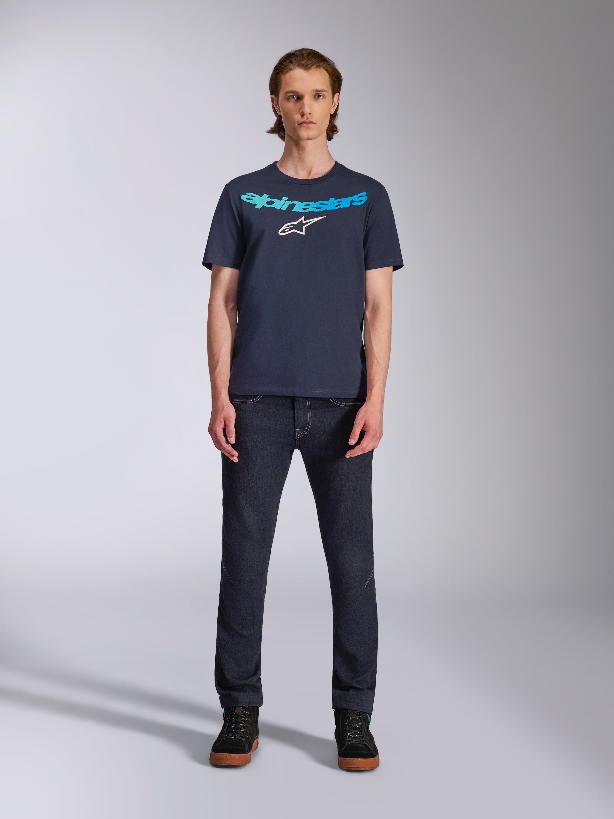 Alpinestars Collared CSF Tee, Kurzarm-T-Shirt, Navyblau, mit hellblauem Alpinestars-Schriftzug und weißem Stern-Logo auf der Brust, getragen von einem Model mit dunklen Denim-Jeans, lässige Motorsport-Streetwear