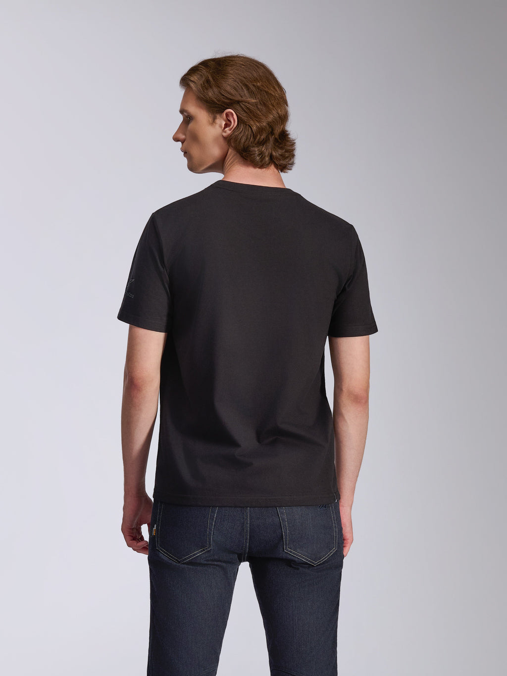 Alpinestars Global CSF Tee, Short Sleeve T-Shirt, Black, back view worn by a model, paired with dark blue jeans, casual motorsport streetwear