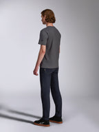 Alpinestars Waving CSF Tee, Kurzarm-T-Shirt, Anthrazit, Rückansicht am Model, kleines schwarzes Stern-Logo am Ärmel, getragen mit dunklen Denim-Jeans und schwarzen Sneakern, lässige Motorsport-Streetwear