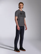 Alpinestars Waving CSF Tee, Kurzarm-T-Shirt, Charcoal, Grafik mit schwarzer wehender Flagge, getragen von einem Model mit dunkler Jeans und Sneakern, Casual Motorsport Streetwear