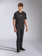 Alpinestars Frontal CSF Tee, Kurzarm-T-Shirt, Schwarz, weißes Astars-Logo auf der Brust, getragen von einem Model mit dunkler Jeans und schwarzen Sneakern, lässige Performance-Streetwear