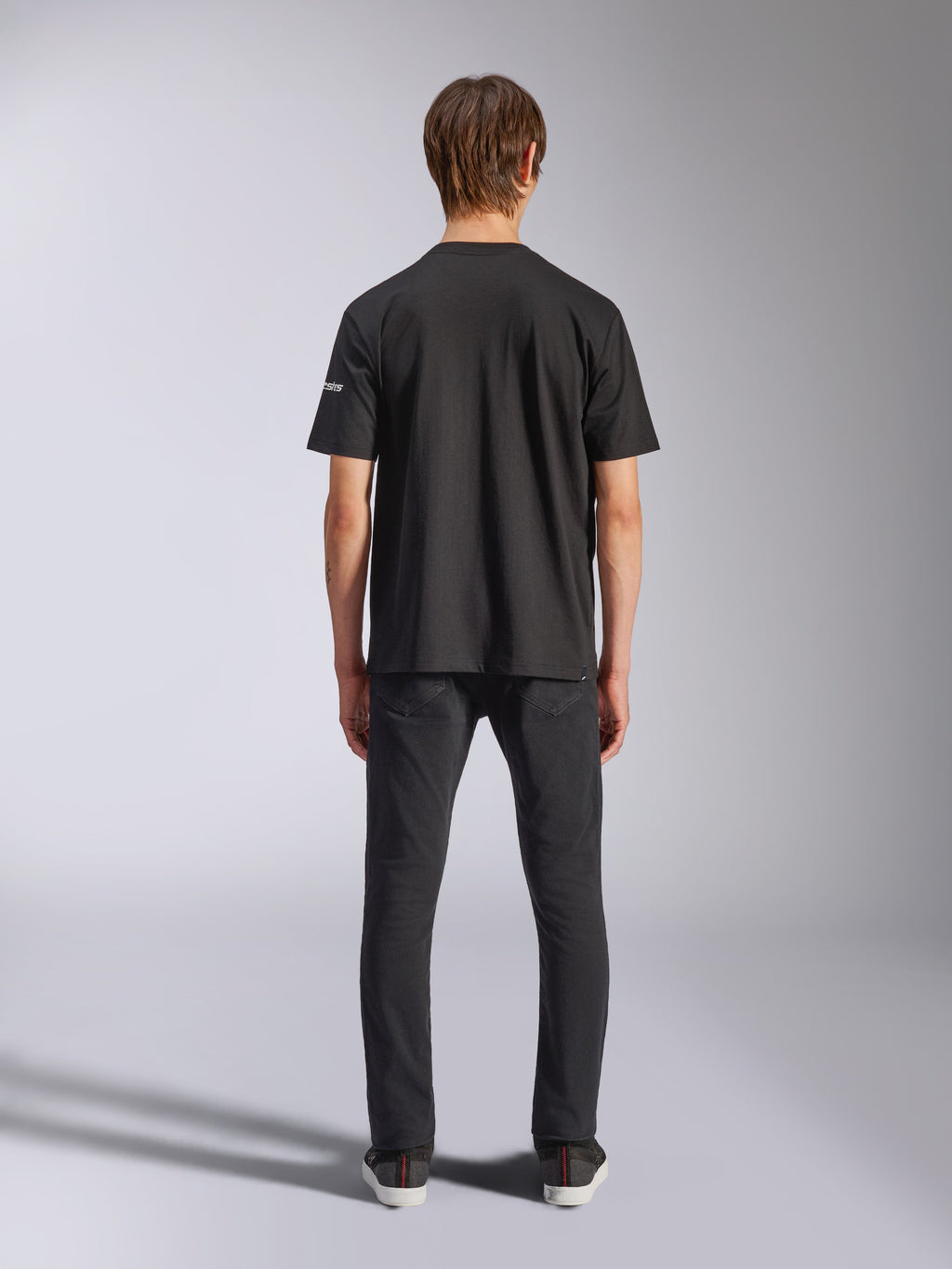 Alpinestars Frontal CSF T-Shirt, Kurzarm, Schwarz, Rückansicht am Model in schwarzen Jeans, lässige Performance-Streetwear mit kleinem weißem Logo-Detail am Ärmel
