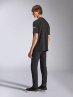 Alpinestars Frontal CSF T-Shirt, kurzärmeliges T-Shirt, Schwarz, weißes Astars-Branding auf dem Ärmel, getragen von einem Model mit schwarzer Hose und Schuhen, lässiges, vom Motorsport inspiriertes Design