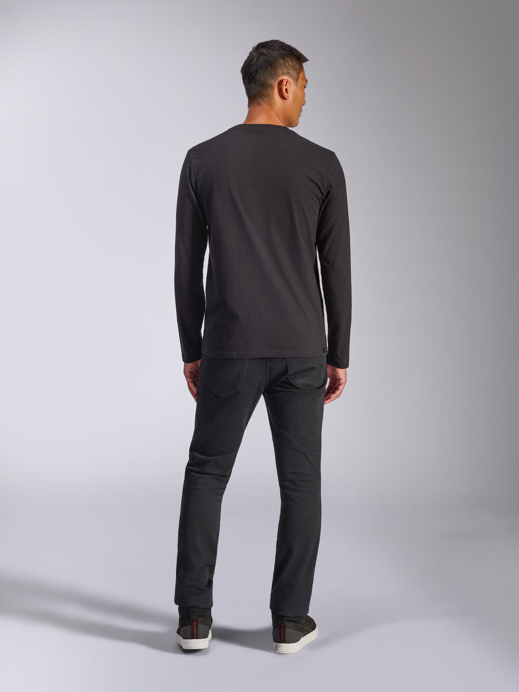 Alpinestars Trackside CSF Tee, Langarm-T-Shirt, Schwarz, Rückansicht eines Models, das das Shirt mit dunkler Hose trägt, lässige, vom Motorsport inspirierte Streetwear