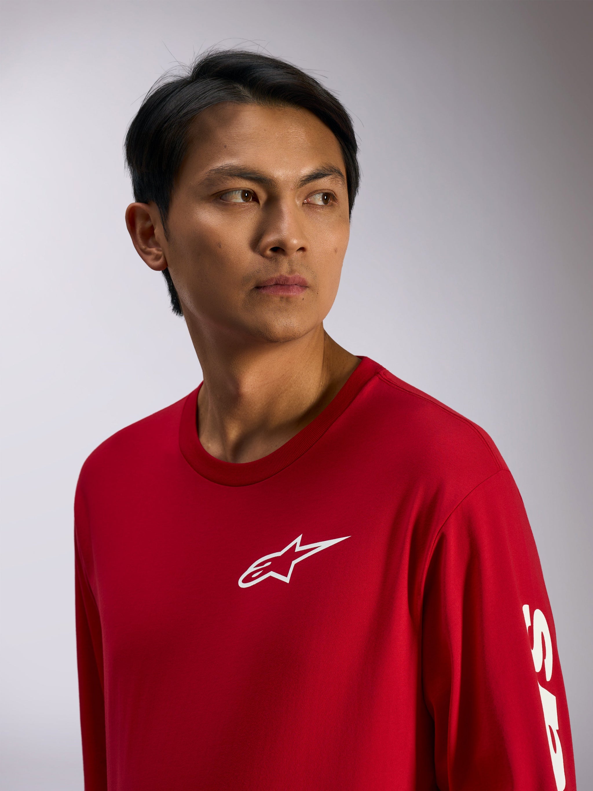 Alpinestars Trackside CSF Tee, Langarmshirt, Rot mit weißem Alpinestars-Logo auf der Brust und Schriftzug am Ärmel, lässige Motorsport-Streetwear, Lifestyle-Porträt