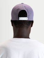 Alpinestars Ageless Snapback Kappe, Sportswear-Cap in Lila und Weiß, Rückansicht am Model mit verstellbarem Snapback-Verschluss und strukturierter Krone