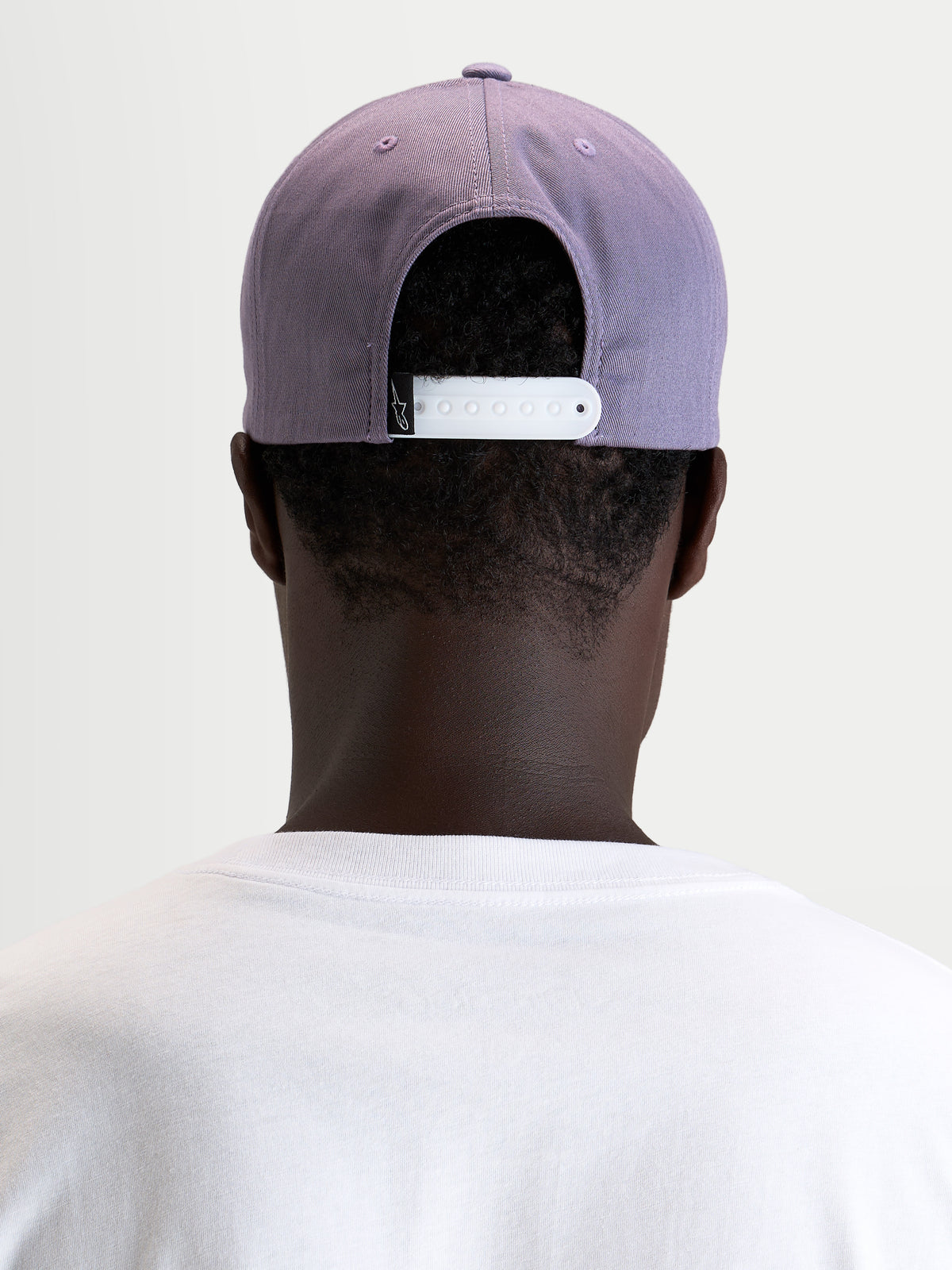 Alpinestars Ageless Snapback Kappe, Sportswear-Cap in Lila und Weiß, Rückansicht am Model mit verstellbarem Snapback-Verschluss und strukturierter Krone