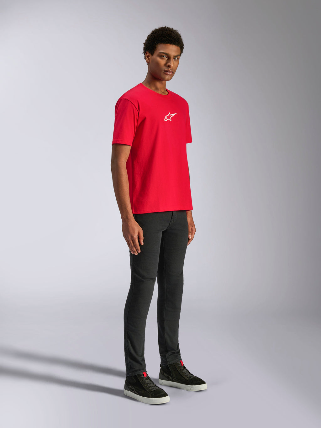 Alpinestars Frontal CSF Tee, Kurzarm-T-Shirt, Rot, weißes Stern-Logo auf der Brust, getragen von einem Model mit schwarzer Hose und schwarzen Sneakern, lässige Motorsport-Performance-Streetwear