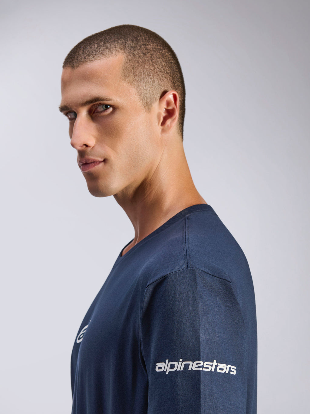 Alpinestars Frontal CSF Tee, Kurzarm-T-Shirt, Marineblau, Seitenprofil eines männlichen Models, weißes Alpinestars-Logo am Ärmel, feuchtigkeitsableitendes Funktionsgewebe, lässiger Motorsport-Lifestyle