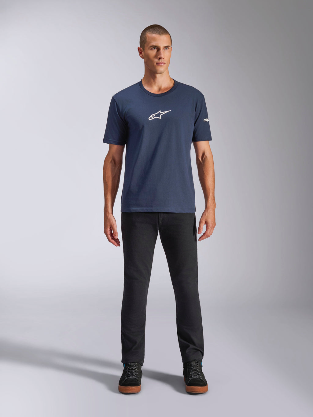 Alpinestars Frontal CSF Tee, Kurzarm-T-Shirt, Marineblau, weißes Alpinestars Stern-Logo auf der Brust, getragen mit schwarzer Hose und Sneakern, lässige Performance-Sportbekleidung