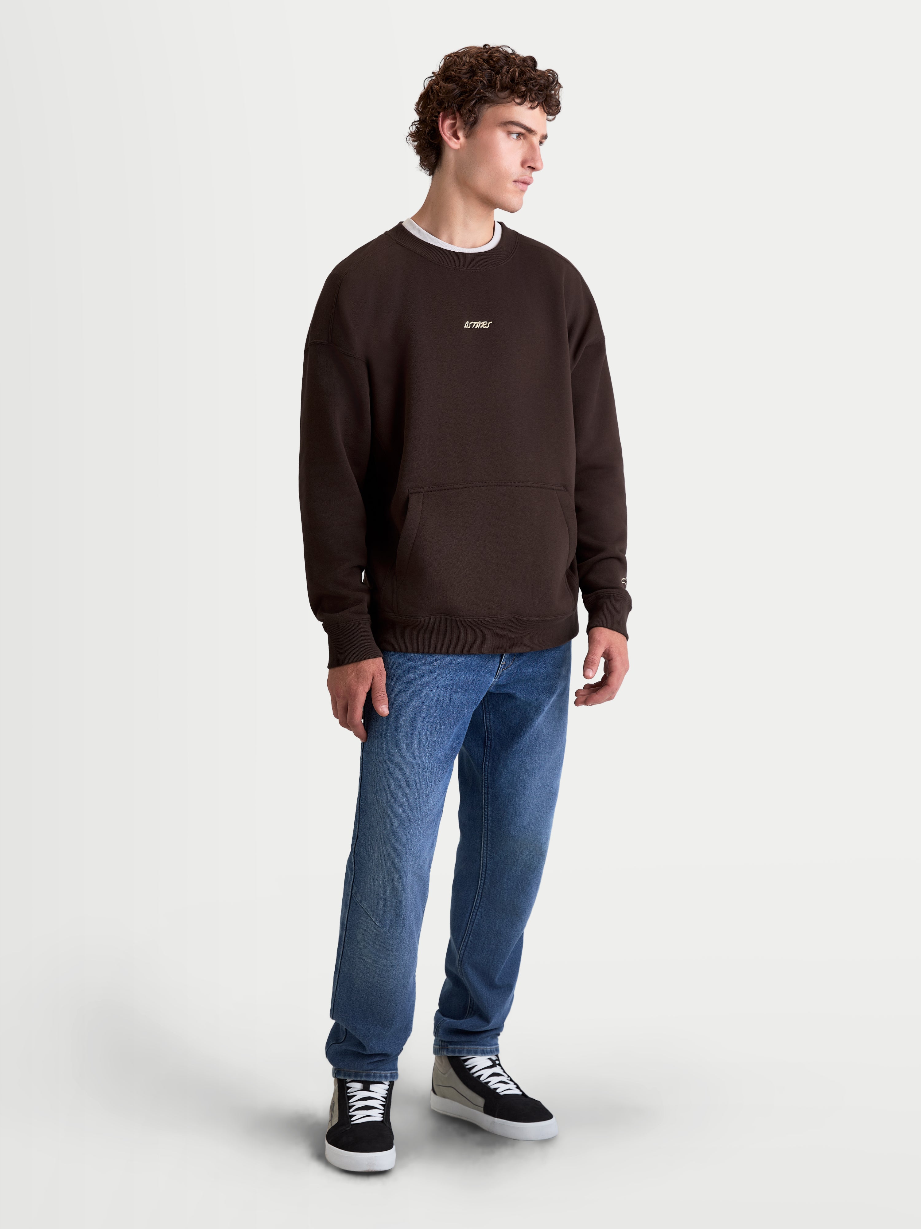 Alpinestars Guise Oversized Crew, brauner Herren-Sportswear-Pullover in Oversized-Passform, mit Rundhalsausschnitt, Kängurutasche und gesticktem Astars-Logo auf der Brust, aus Baumwolle und recyceltem Polyester, Motorsport-Lifestyle-Look, Ansicht am Model.