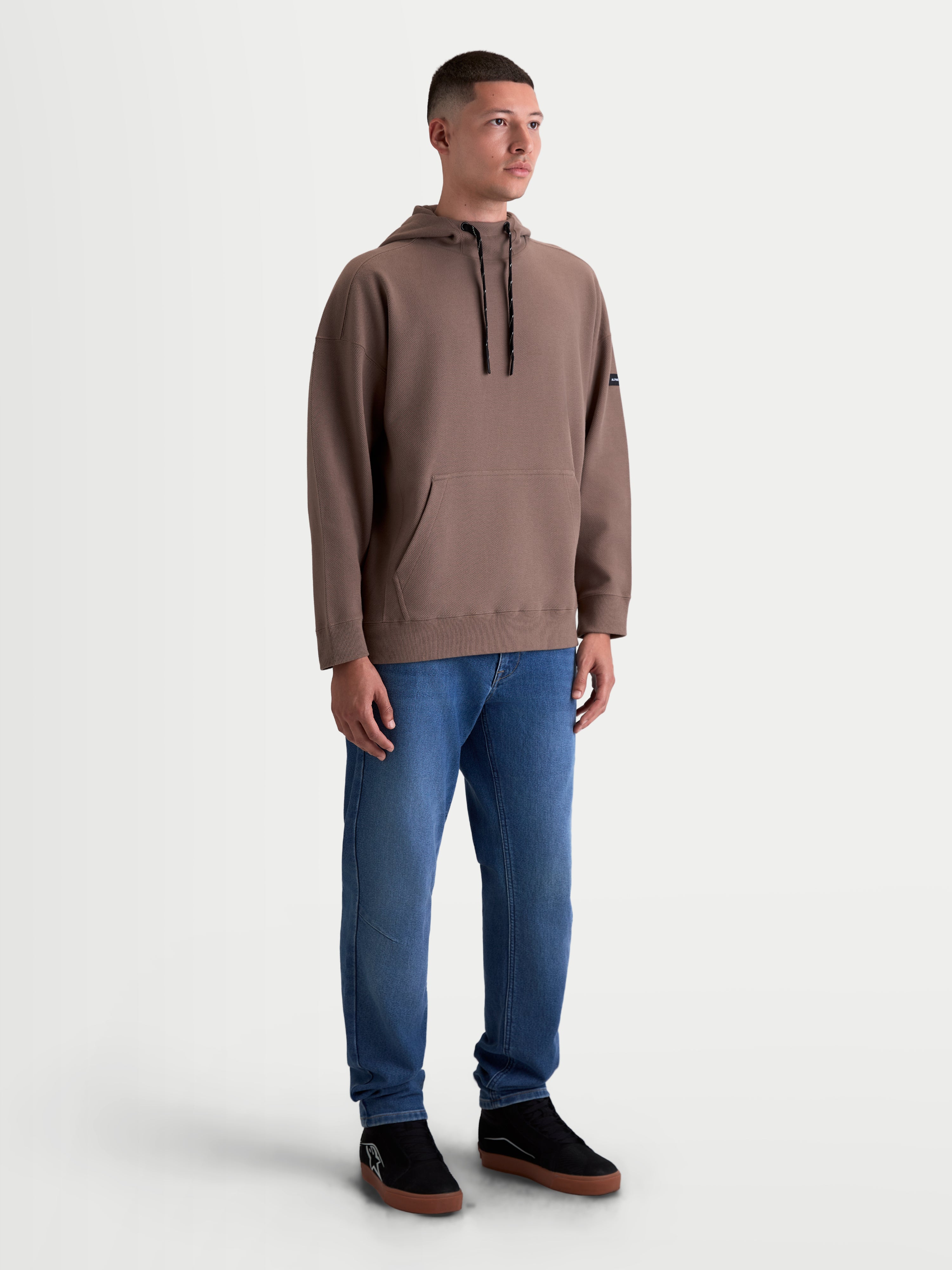 Alpinestars Camino Textured Oversized Hoodie, Kapuzenpullover für Herren und Damen, Braun, strukturiertes Stricktwill-Fleece, hoher Kragen und Kängurutasche, lässige Oversize-Passform, am Model getragen.