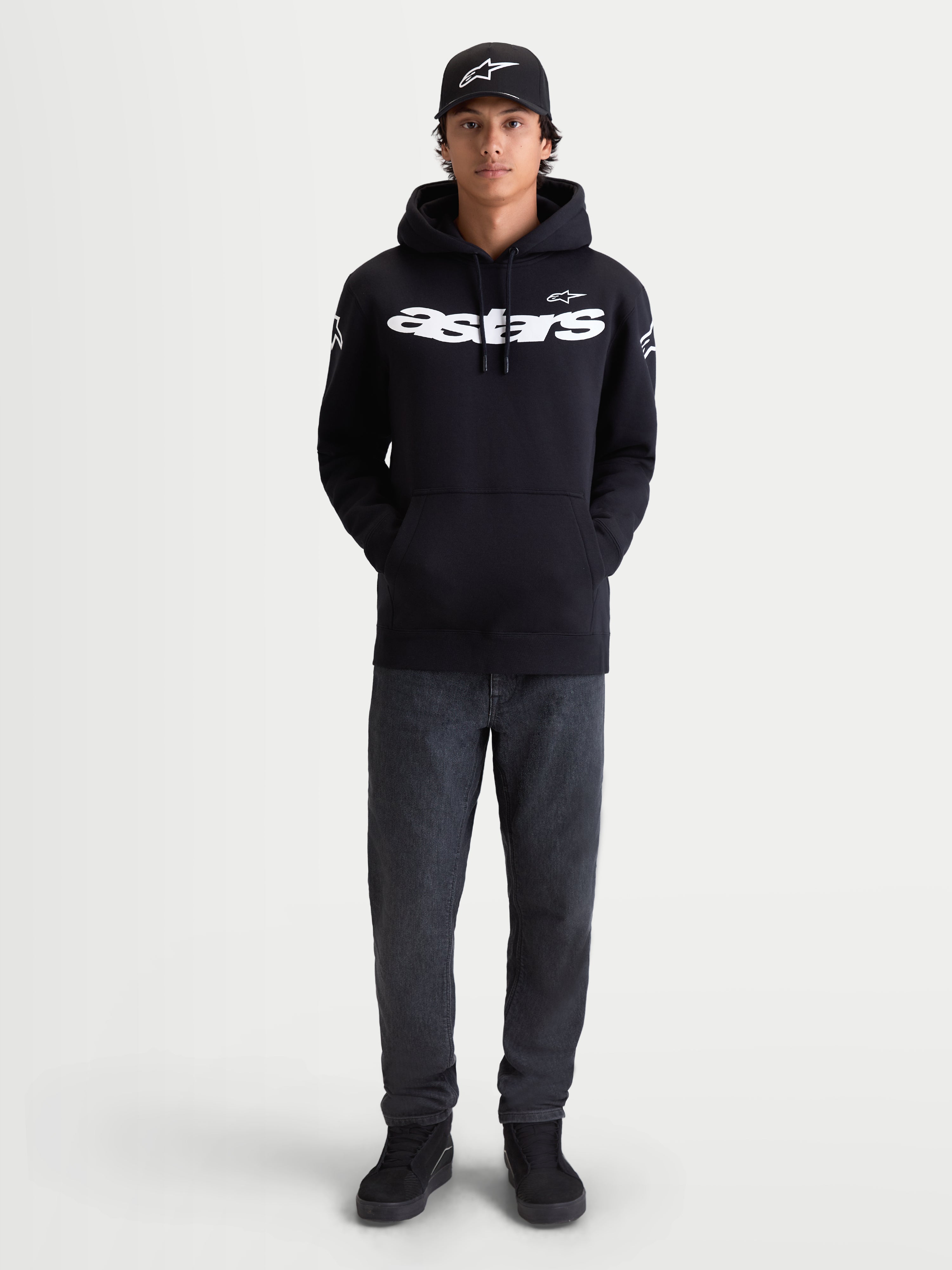 Alpinestars Velocifier Hoodie, Herren-Fleecepullover für die Freizeit, Schwarz und Weiß, Premium-Baumwollmischung, weißer Astars-Schriftzug auf der Brust und Logos an den Schultern, am Modell gezeigt mit passender Kappe.