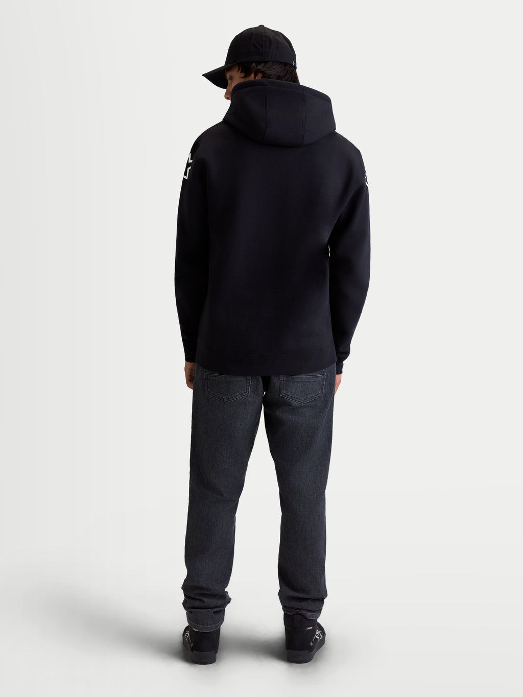 Alpinestars Velocifier Hoodie, Herren-Sportswear-Fleecepullover, Schwarz, Mischung aus Baumwolle und recyceltem Polyester, Rückansicht am Modell mit Kapuze und weißen Alpinestars-Logos an den Schultern.