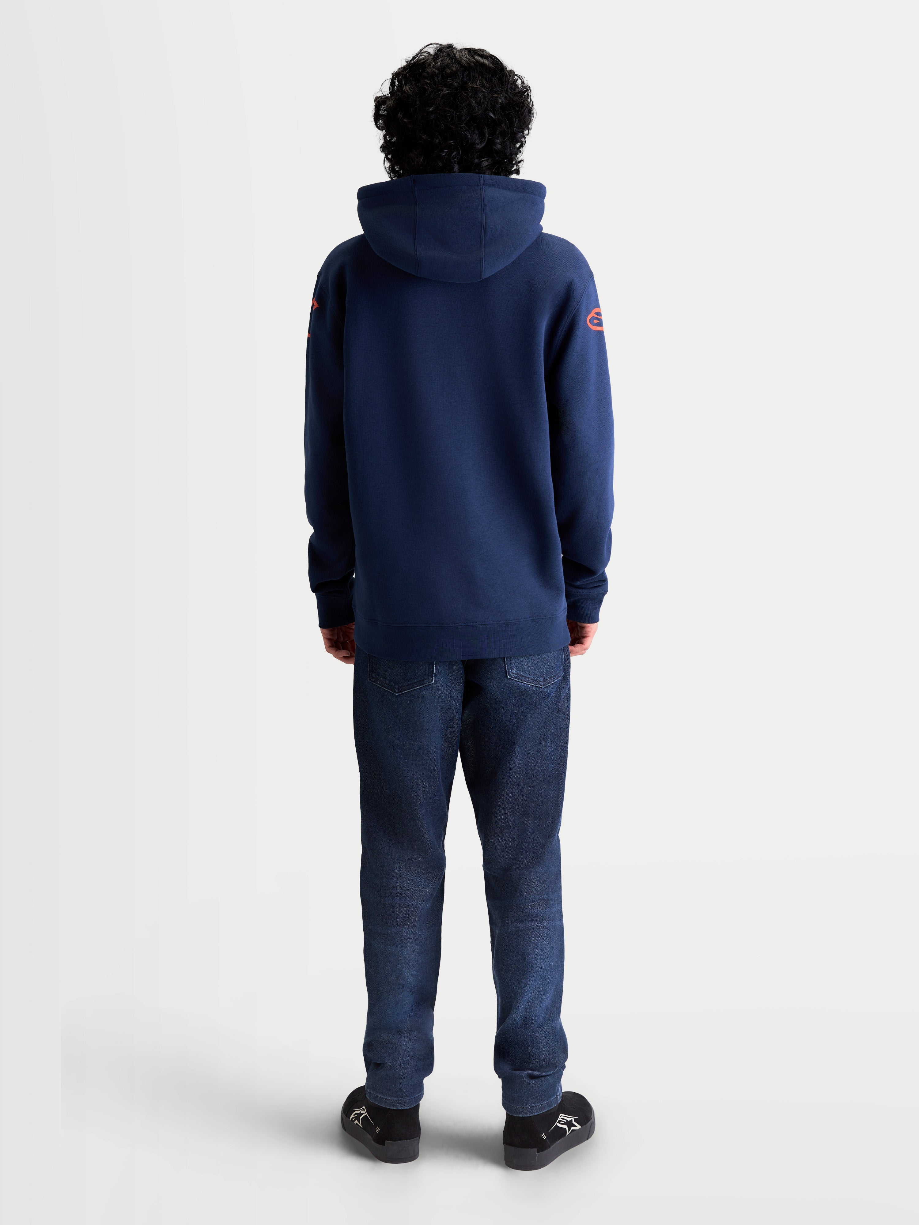 Alpinestars Velocifier Hoodie, Sportswear-Kapuzenpullover aus Fleece, Navyblau mit roten Astars-Logos an den Schultern, Rückansicht am Modell, Premium-Mischgewebe aus Baumwolle und recyceltem Polyester für Casual-Style abseits des Bikes.