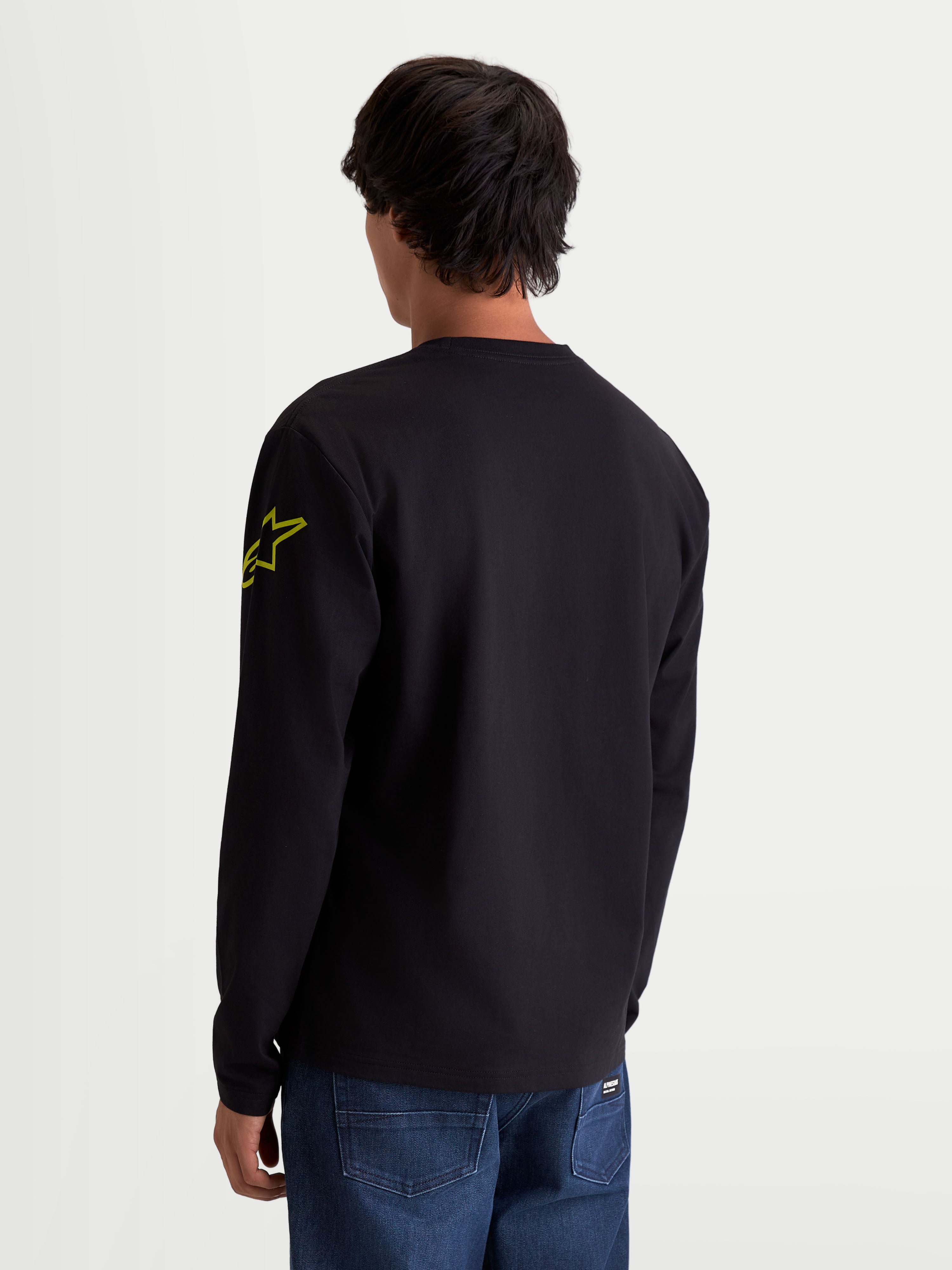 Alpinestars Velocifier CSF T-Shirt, Langarm-T-Shirt für Sport und Freizeit, Schwarz und Gelb, Rückansicht am Model zeigt das gelbe Astars-Logo am Arm und Rippbündchen, Mischung aus Baumwolle und recyceltem Polyester.