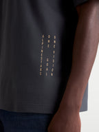 Alpinestars Chalk Oversized CSF Tee, Short Sleeve Sportswear T-shirt, Charcoal Gray, on-model close-up showing the vertical Alpinestars and One Goal One Vision side branding near the hem, premium cotton-poly blend construction.