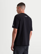 Alpinestars Mandate Oversized CSF T-Shirt, Herren Kurzarm-T-Shirt in Schwarz, Rückansicht mit weißen Wortmarken-Logos im Nacken und am Ärmel, lockere Oversized-Passform für lässigen Sportswear-Komfort.