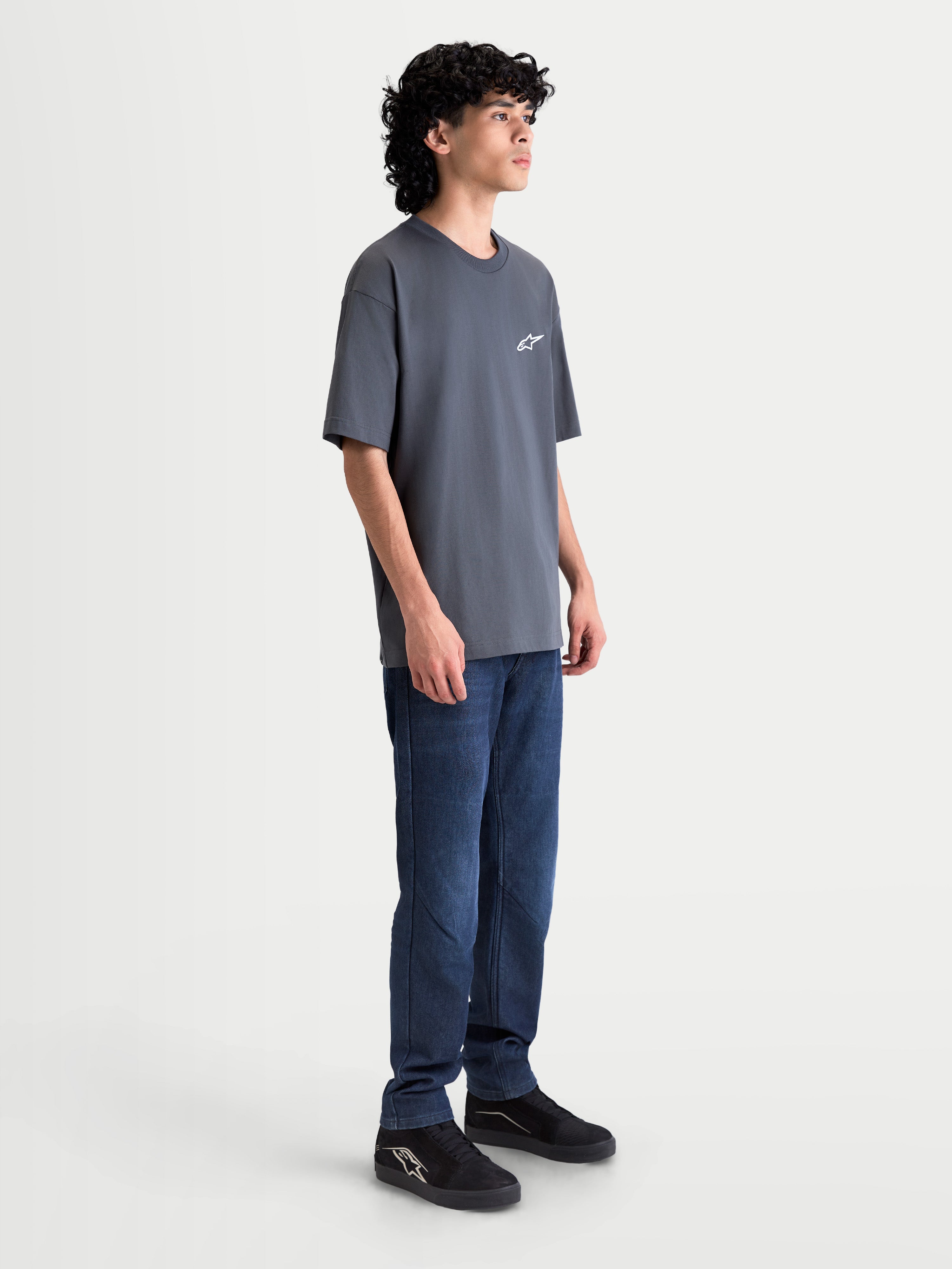 Alpinestars Mandate Oversized CSF Tee, Unisex Short Sleeve Sportswear T-Shirt, Gray Charcoal, featuring a relaxed oversized fit and puff-print Astars logo, shown on model side view.
