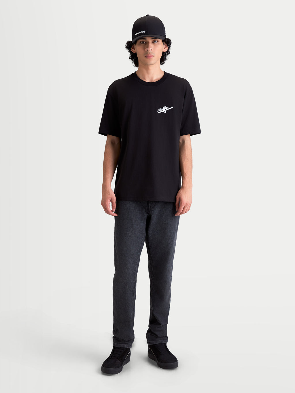 Alpinestars Meteor CSF T-Shirt, Kurzarm-Sportswear-T-Shirt, Schwarz mit weißem Astars-Logo auf der Brust, bequeme Baumwoll-Polyester-Mischung, lässiger Motorsport-Look am Model.