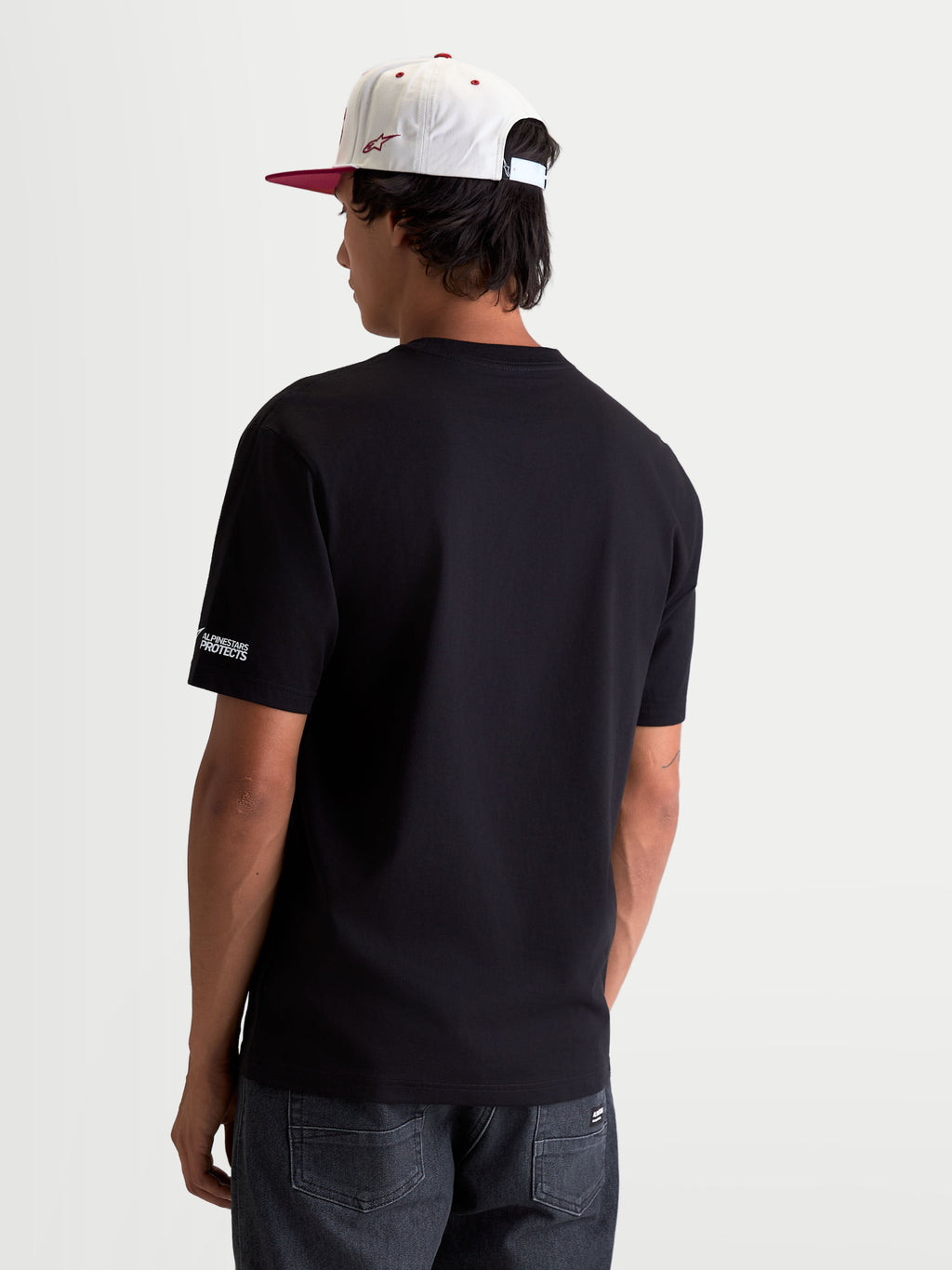 Alpinestars P1 CSF T-Shirt, Kurzarm-Motorsport-T-Shirt, Unisex, Schwarz, aus komfortablem Baumwoll-Polyester-Mix, Rückenansicht auf Modell mit dezentem Alpinestars Protects-Logo am Ärmel, Alltagskleidung im Motorsport-Stil.