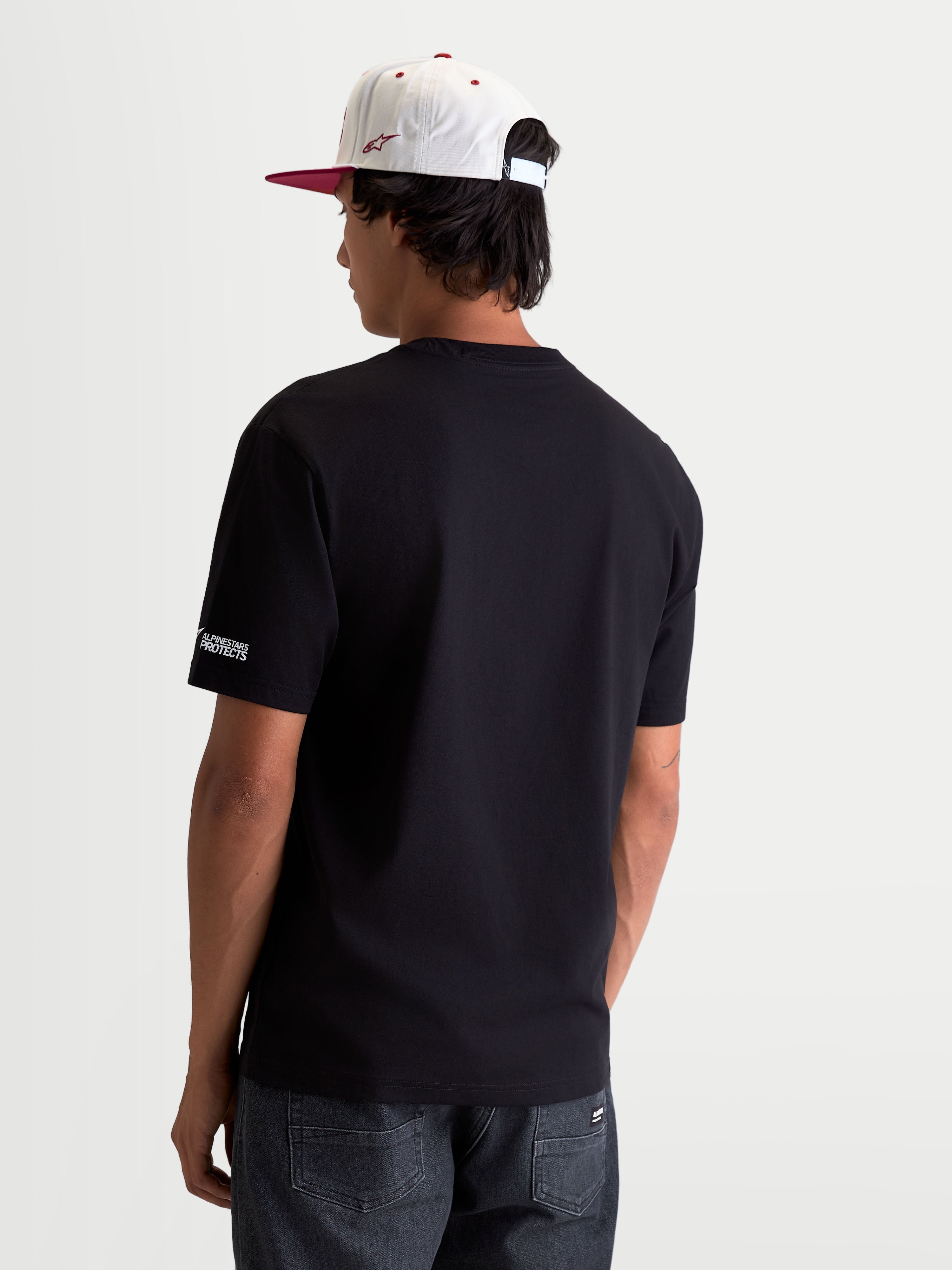 Alpinestars P1 CSF T-Shirt, Kurzarm-Motorsport-T-Shirt, Unisex, Schwarz, aus komfortablem Baumwoll-Polyester-Mix, Rückenansicht auf Modell mit dezentem Alpinestars Protects-Logo am Ärmel, Alltagskleidung im Motorsport-Stil.