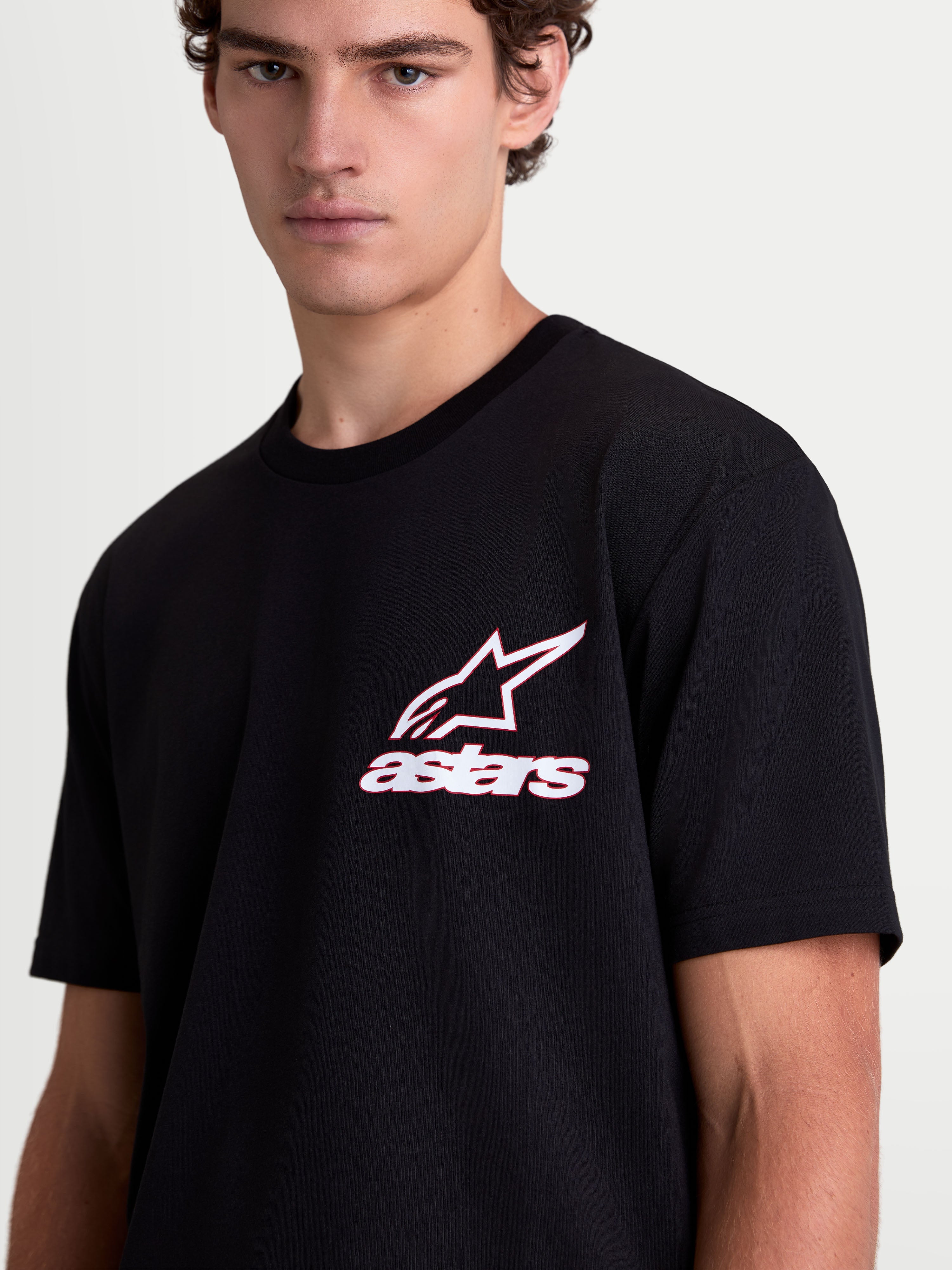 Alpinestars Lineout CSF T-Shirt am Modell, Kurzarm-Sportswear-T-Shirt in Schwarz mit weißer und roter Astars-Logo-Grafik auf der Brust, Baumwoll-Polyester-Mix, lässige Lifestyle-Mode für Herren und Damen.