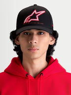 Alpinestars Lineout Kappe, Sportswear-Baseballkappe mit gebogenem Schirm, Schwarz mit rot-weiß besticktem Astars-Logo und One Goal One Vision Branding, Frontansicht am Modell in einem roten Kapuzenpullover, strukturierte Twill-Konstruktion.