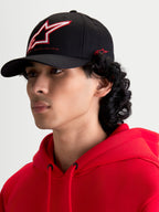 Alpinestars Lineout Kappe, schwarze Sportswear-Kappe mit gebogenem Schirm, getragen von einem Model. Die Kappe verfügt über eine strukturierte Krone mit rot-weiß gesticktem Astars-Logo und seitlichem Branding.
