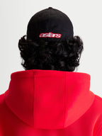 Alpinestars Lineout Kappe, Sportswear-Baseballkappe in Schwarz und Rot, Rückansicht am Modell mit besticktem Astars-Logo, strukturierte Krone, Twill-Gewebe-Konstruktion.
