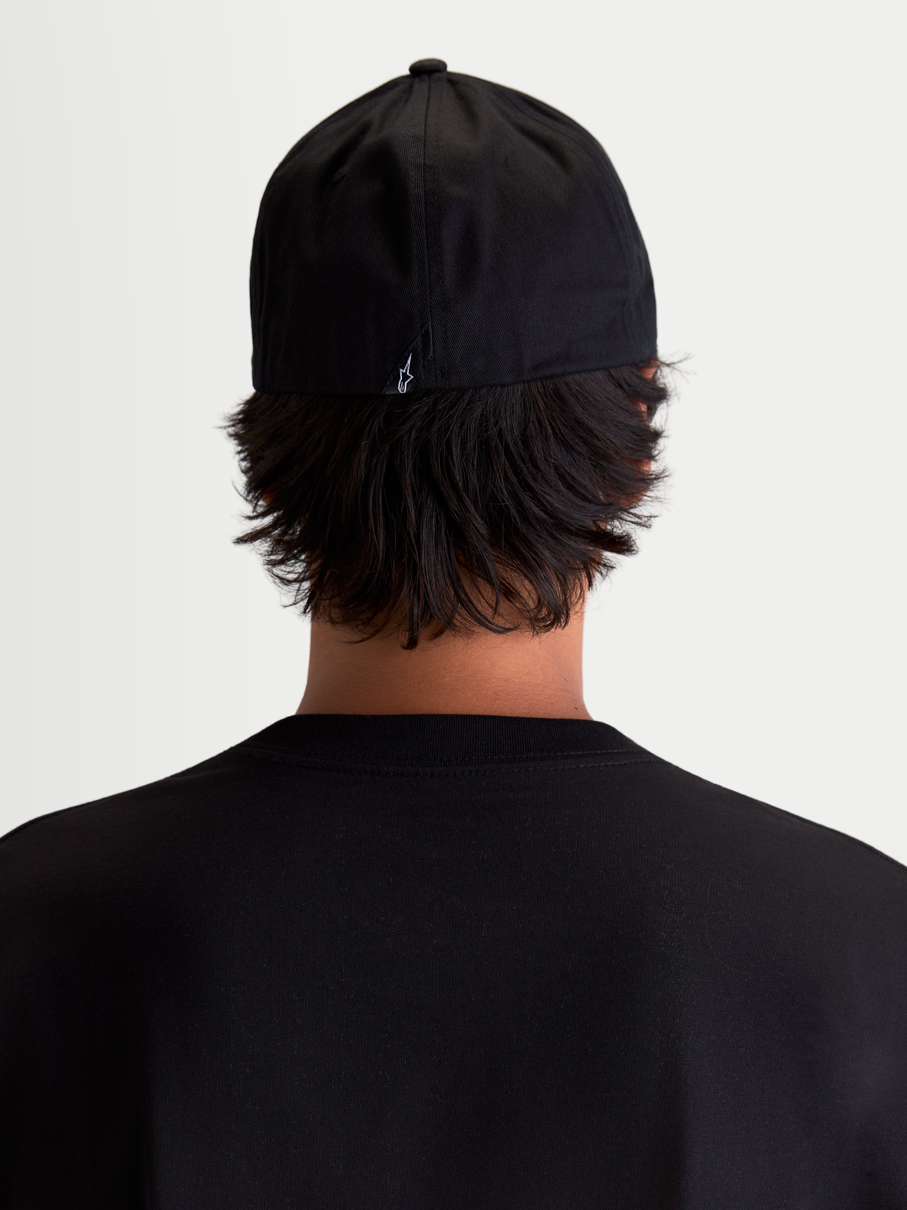 Alpinestars Arclight Kappe, schwarze Sportswear Baseball-Kappe, Rückansicht am Modell, mit kleinem weißem Astars-Logo auf der Rückseite, strukturierte Krone und Flex-Back-Konstruktion, strapazierfähiger Baumwoll-Twill für täglichen Tragekomfort.