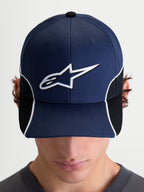 Alpinestars 500 Snapback Kappe, Motorsport-inspirierte Sportswear-Kappe, Unisex, Marineblau und Schwarz, mit gebogenem Schirm und 3D-gesticktem weißem Astars-Logo, Kontrastpaspelierung und Cut-and-Sew-Details, Frontansicht am Model.
