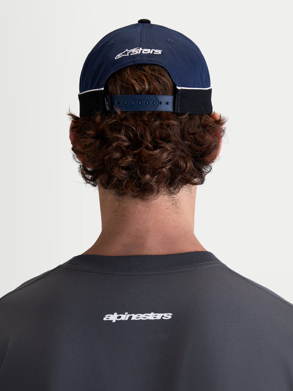 Alpinestars 500 Snapback Kappe, Motorsport-Sportswear-Baseballkappe, Navyblau und Schwarz, 100 % Baumwolltwill-Konstruktion mit verstellbarem Snapback-Verschluss und gesticktem Astars-Logo, Rückansicht am Modell.