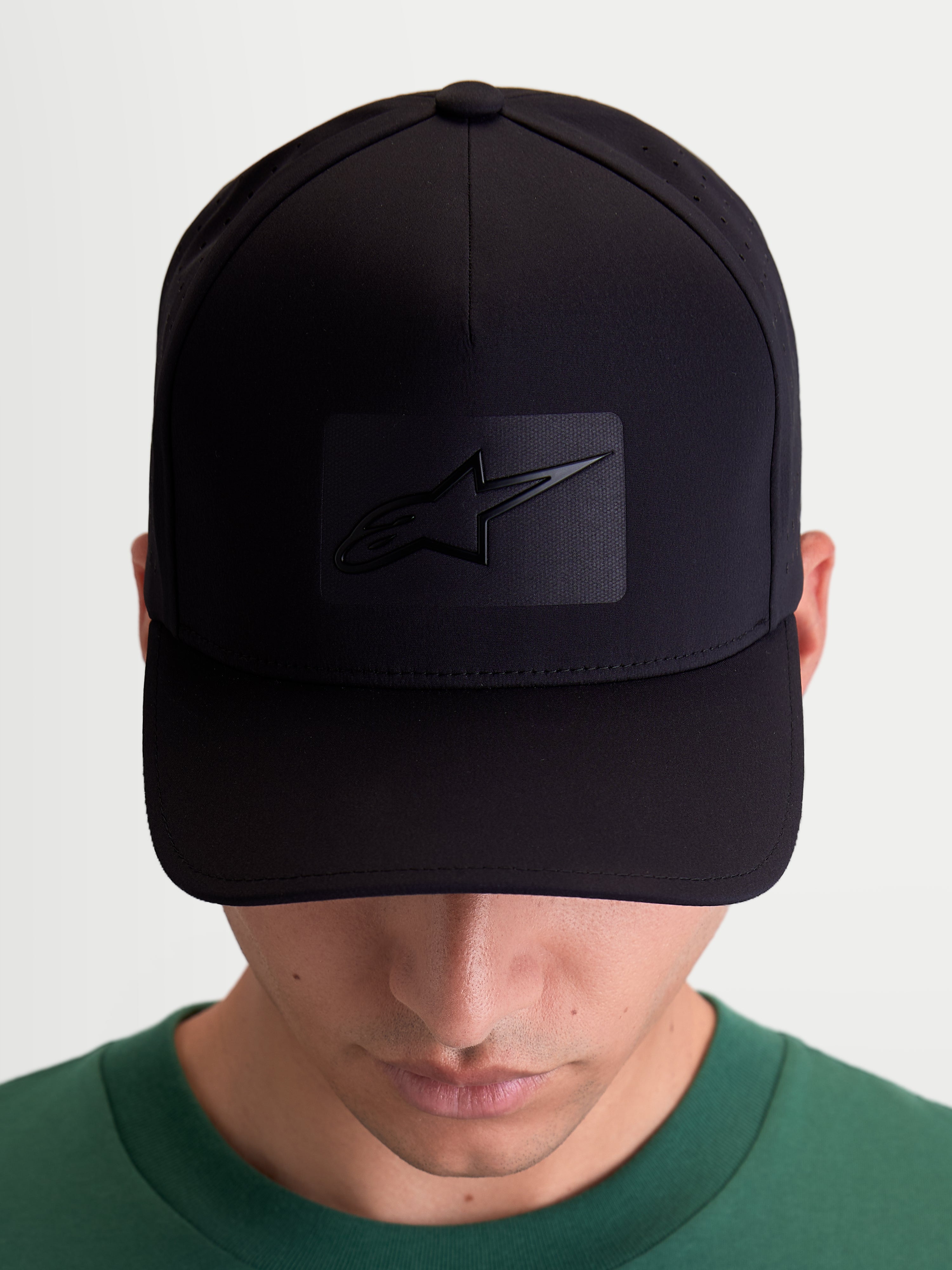 Alpinestars Algo Perf Adjustable Hat, Sportswear Baseball Cap for Men and Women, Black Technical Fabric with Side Perforations, Curved Bill and Structured Crown, Front View on Model showing Sonic-Weld Astars Logo.