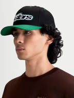 Alpinestars Retro Snapback Kappe, Sportswear-Cap getragen von männlichem Model, Schwarz und Grün, mit gebogenem Schirm, strukturierter Krone und gesticktem Astars-Logo mit grünem Zierstich, Baumwoll-Twill.