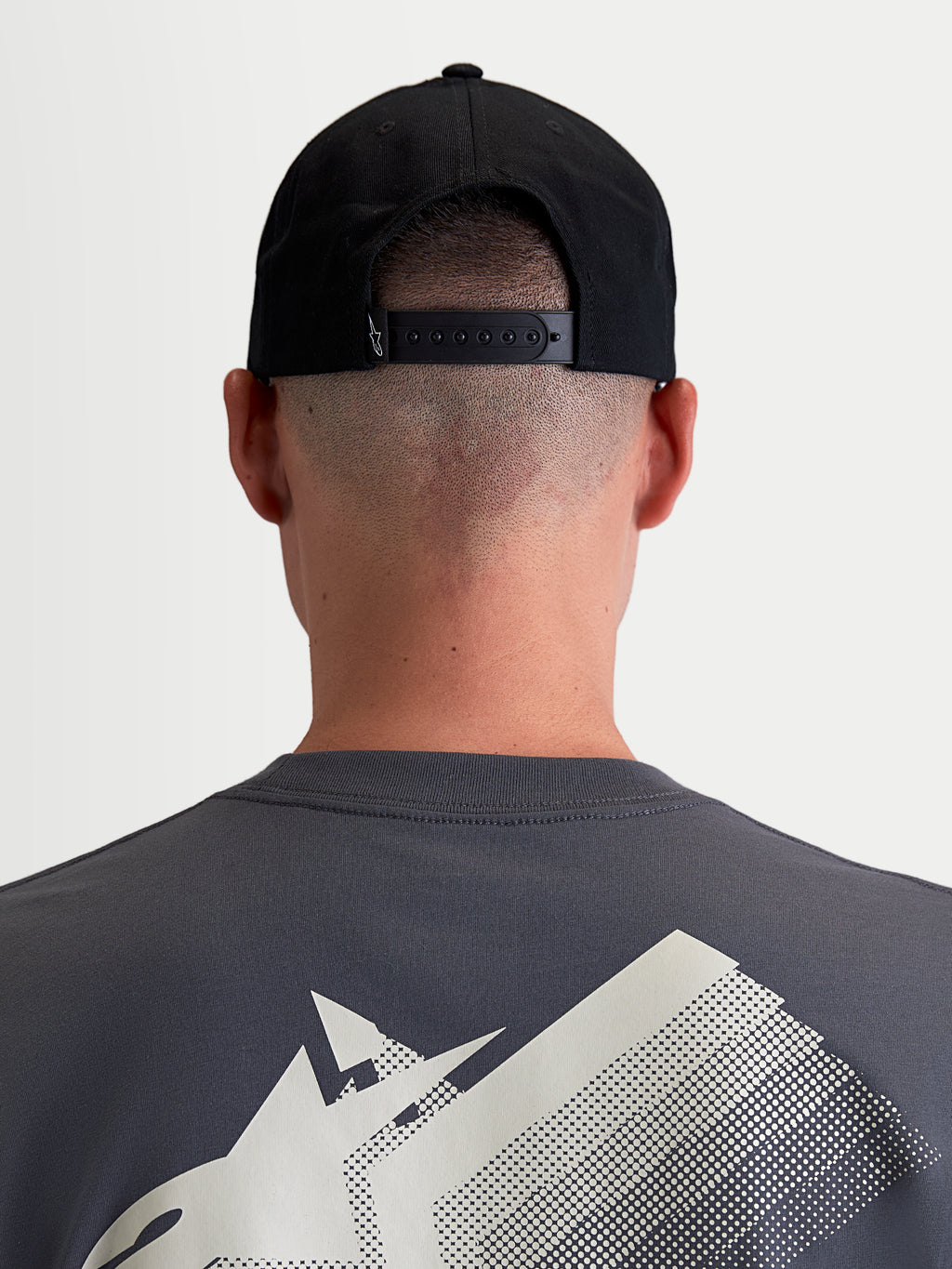Alpinestars Combo Logo Snapback-Kappe, Sportswear-Cap für Damen und Herren, Schwarz, strapazierfähiger Baumwoll-Twill, Rückansicht am Model zeigt den verstellbaren Snapback-Verschluss und ein kleines weißes Logo-Detail.