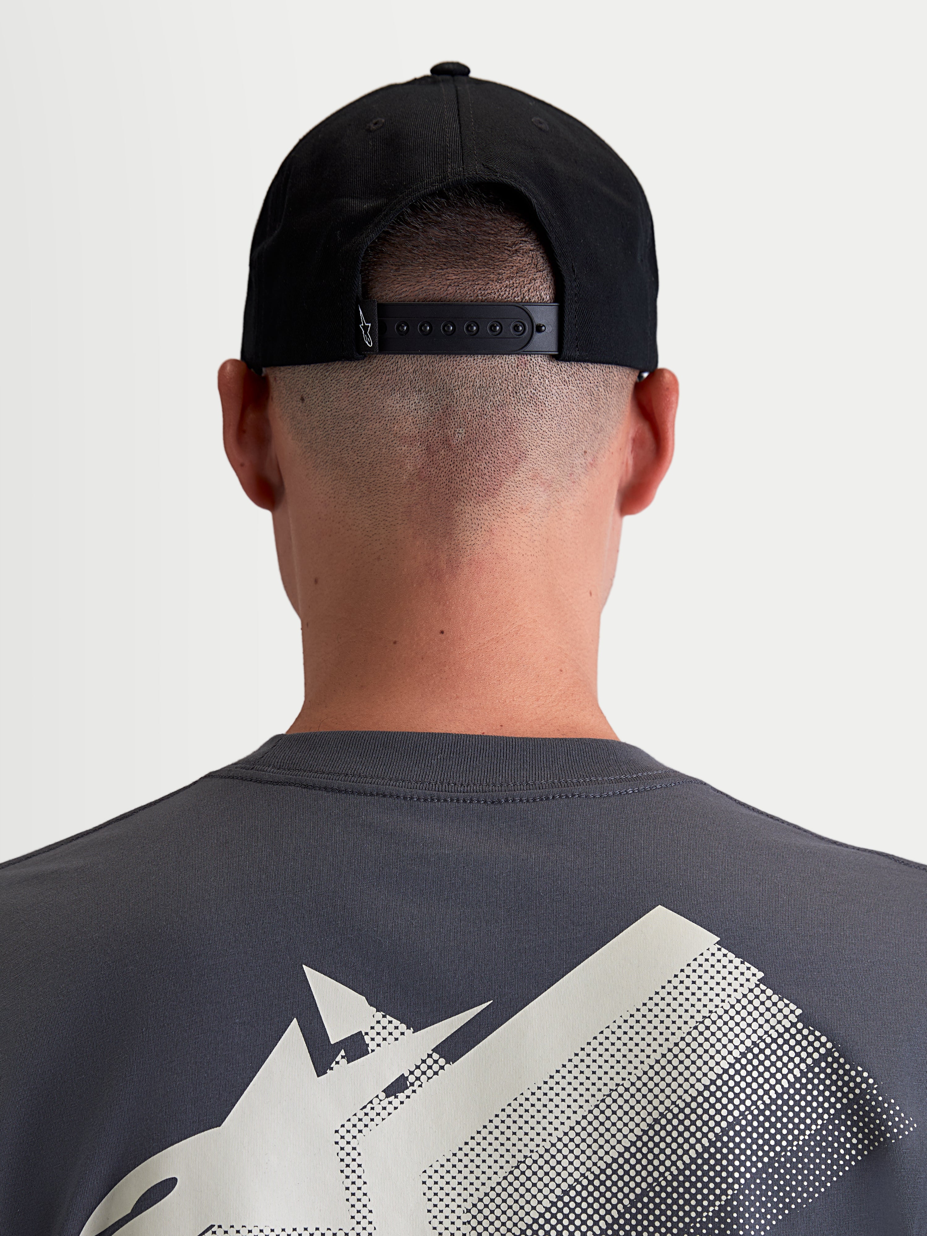 Alpinestars Combo Logo Snapback-Kappe, Sportswear-Cap für Damen und Herren, Schwarz, strapazierfähiger Baumwoll-Twill, Rückansicht am Model zeigt den verstellbaren Snapback-Verschluss und ein kleines weißes Logo-Detail.