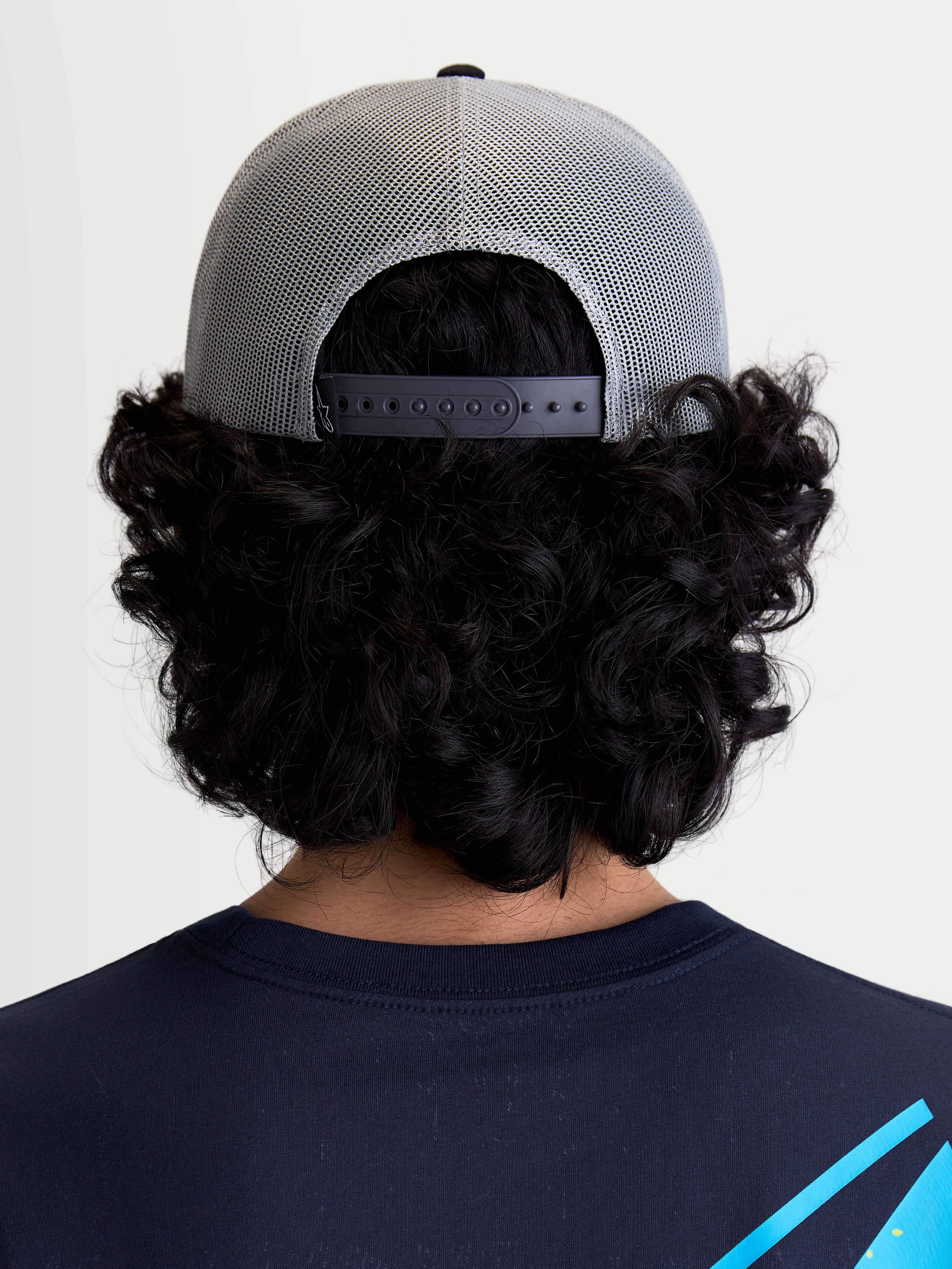 Alpinestars Gravel Trucker-Kappe, Sportswear-Kappe in Grau und Schwarz, Rückansicht am Modell mit atmungsaktiver Poly-Mesh-Rückseite und verstellbarem Snapback-Verschluss für eine individuelle Passform.