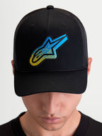 Alpinestars Meteorite Trucker Hat, Sportswear Mesh Back Cap, Black and Blue, featuring a textured Astars logo patch, structured crown, and curved bill, worn by a model.