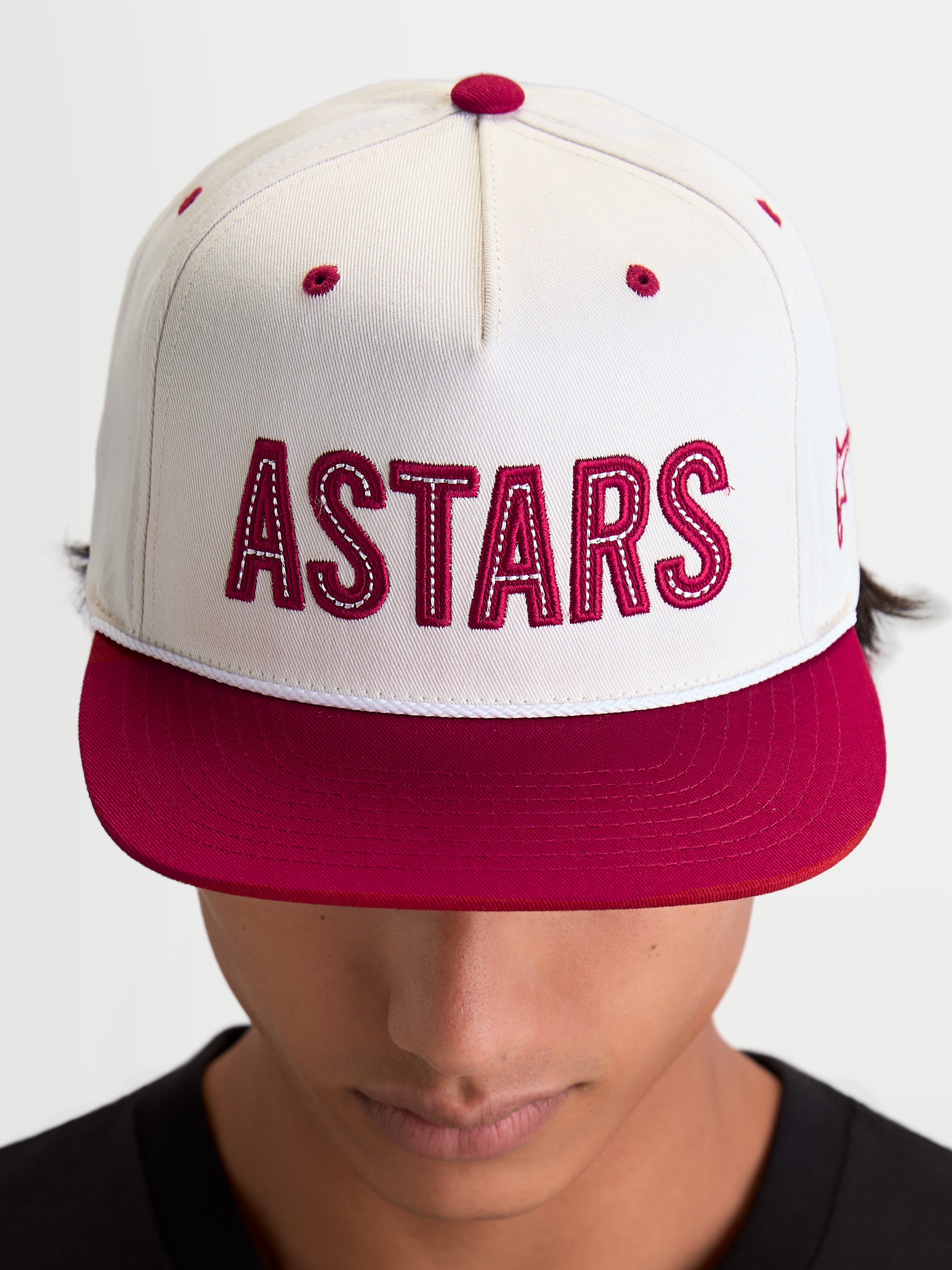 Alpinestars Stadium Snapback Kappe, Sportswear-Kappe mit flachem Schirm, Off-White und Rot, mit markanter 'ASTARS' Logo-Applikation auf der Vorderseite, Kontrastnähten und einer strukturierten Krone, am Modell getragen.