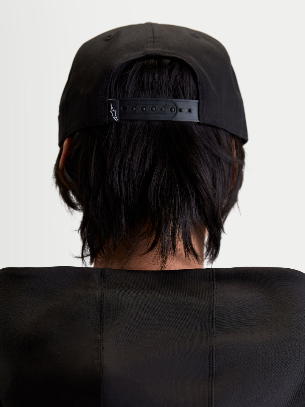 Alpinestars Label Snapback Kappe, schwarze Sportswear-Kappe, Rückansicht am Modell mit verstellbarem Snapback-Verschluss und kleinem weißen Logo, strukturierte Konstruktion aus Baumwoll-Twill.