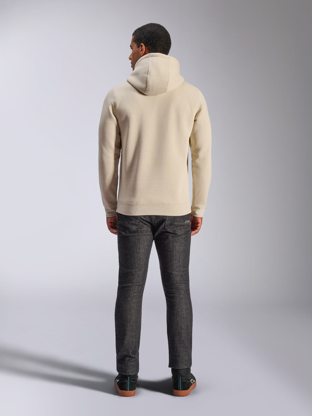 Alpinestars Ageless V3 Hoodie, Rückansicht, Off-White Kapuzenpullover, lässige Lifestyle-Bekleidung, getragen mit dunkelgrauen Jeans, Rippbündchen an Saum und Ärmeln, klares minimalistisches Design