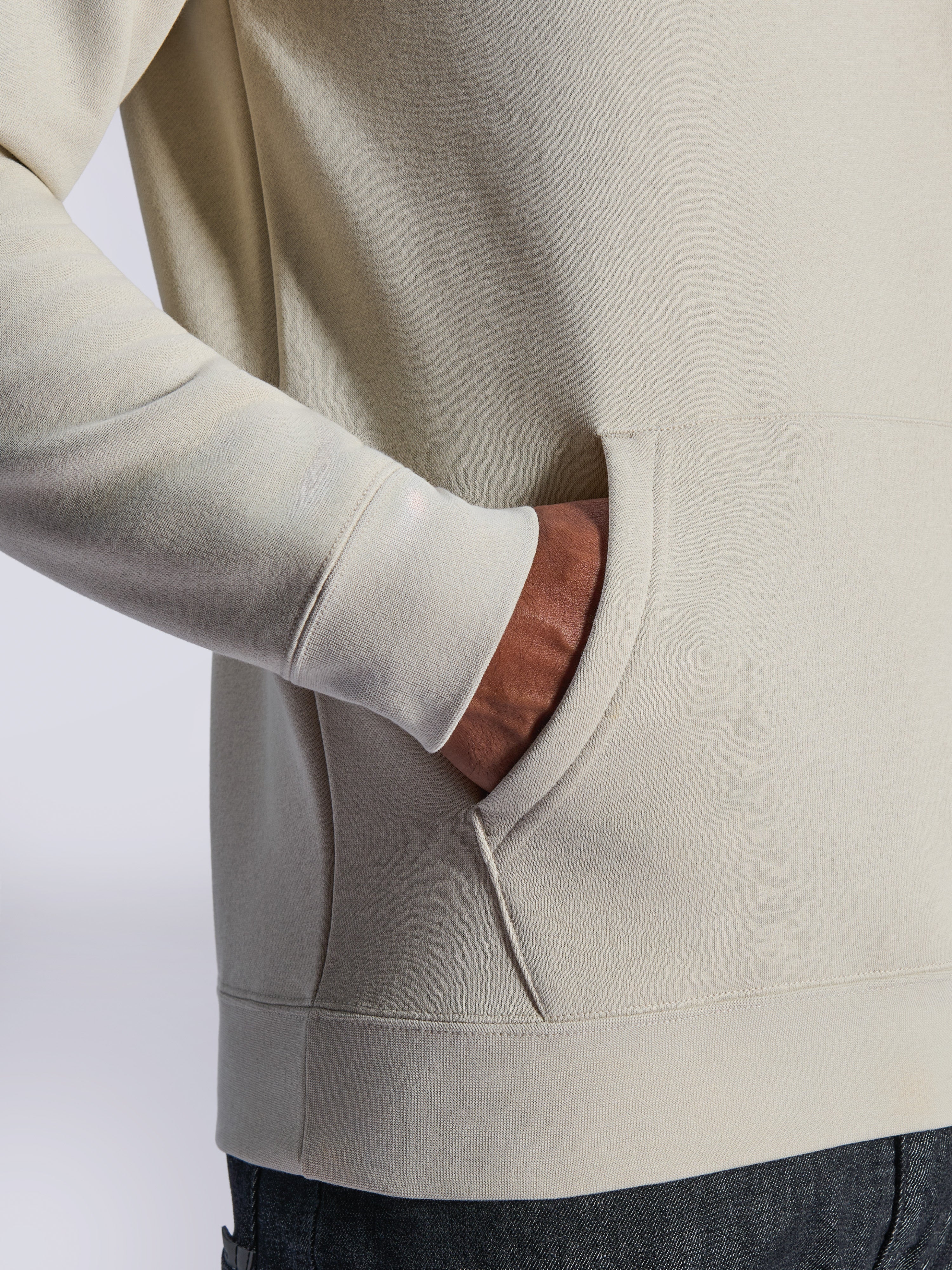 Alpinestars Ageless V3 Hoodie, Nahaufnahme der vorderen Kängurutasche und des Rippbündchens, Fleece in Off-White, lässige vom Motorsport inspirierte Streetwear