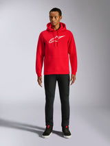 Alpinestars Ageless V3 Hoodie, lässige Streetwear, Rot mit weißem gesticktem Alpinestars-Logo, getragen von einem männlichen Model mit schwarzer Hose, Kapuze mit Kordelzug, Kängurutasche vorne, modernes, vom Motorsport inspiriertes Design