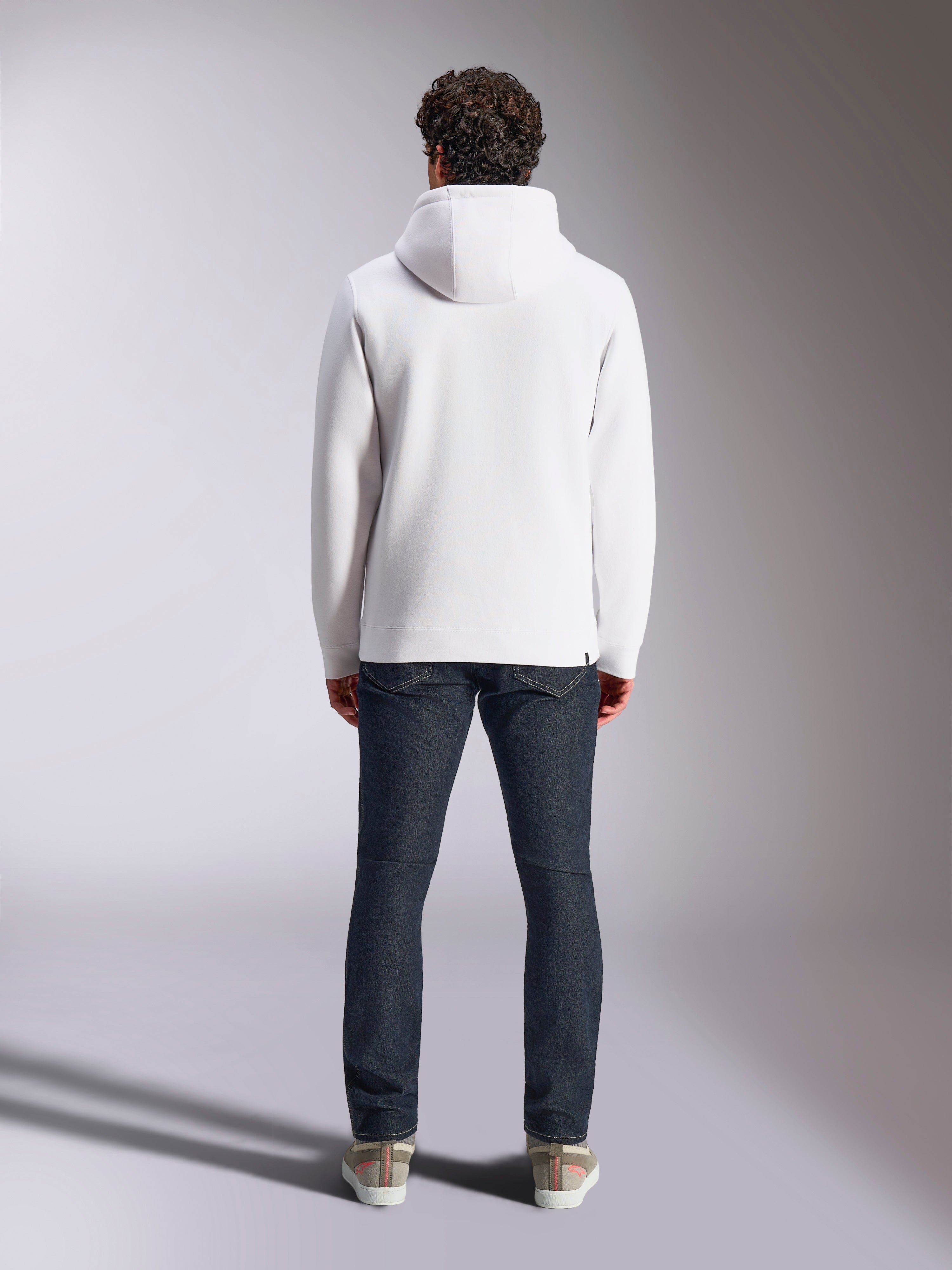 Alpinestars Blaze V3 Hoodie, white casual sportswear hoodie, back view of pullover fleece, clean design with ribbed cuffs and hem, styled with dark blue jeans and sneakers, modern motorsport-inspired lifestyle wear