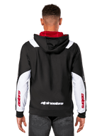 Alpinestars Sessions V3 Hoodie, Rückansicht, Schwarz mit weißen Ärmeleinsätzen und rotem Kapuzenfutter, mit weißem Schriftzug am Rücken und rotem Branding an den Ärmeln, lässige, vom Motorsport inspirierte Streetwear