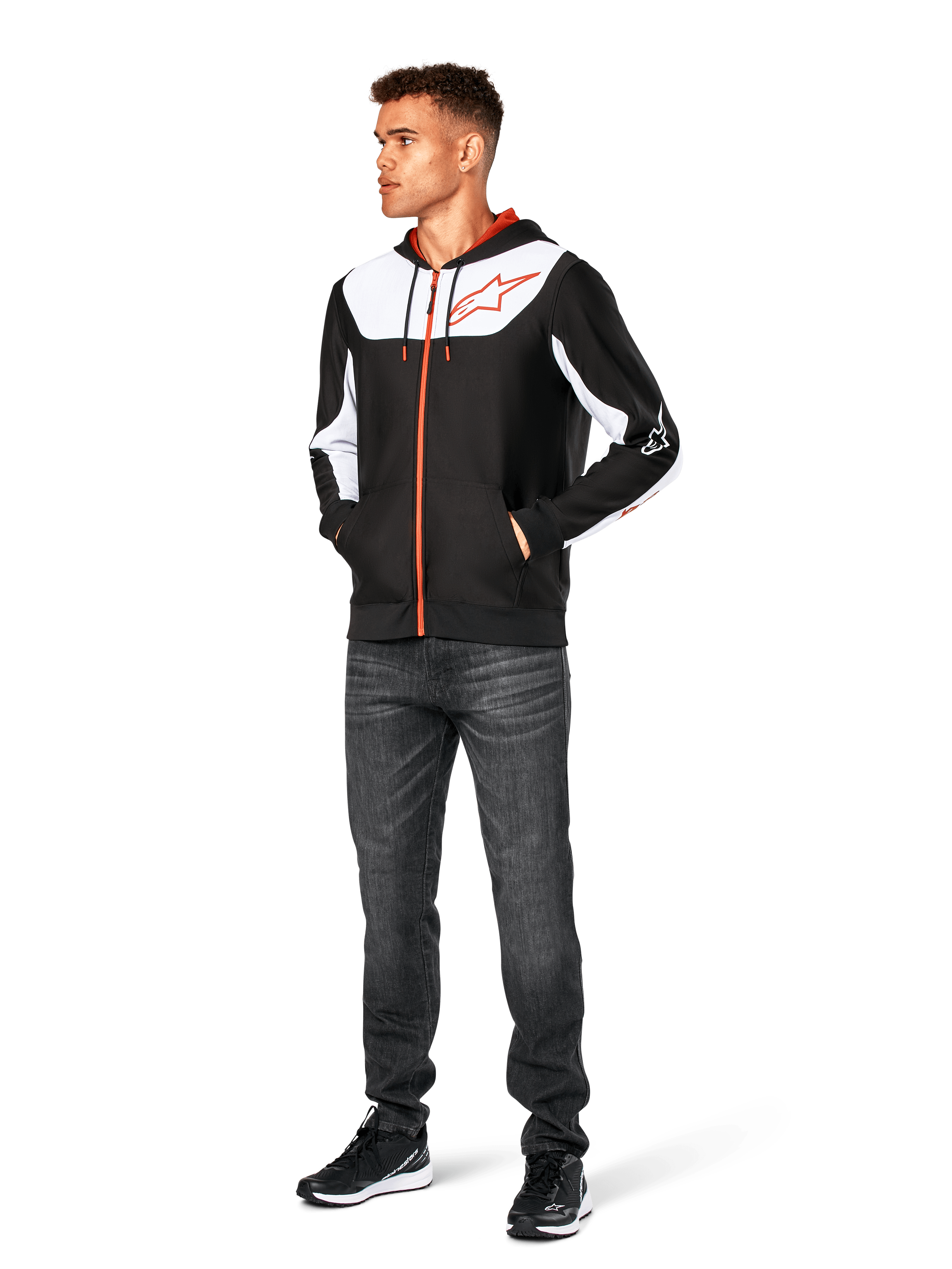Alpinestars Sessions V3 Hoodie, lässige Kapuzenjacke mit Reißverschluss, Schwarz, Weiß und Rot, getragen von einem Model mit dunkler Jeans und schwarzen Sneakern, mit weißen Color-Block-Einsätzen an Brust und Ärmeln, rotem Reißverschluss und Kordelzug, großem Brustlogo, Poly-Fleece, vom Motorsport inspirierte Streetwear