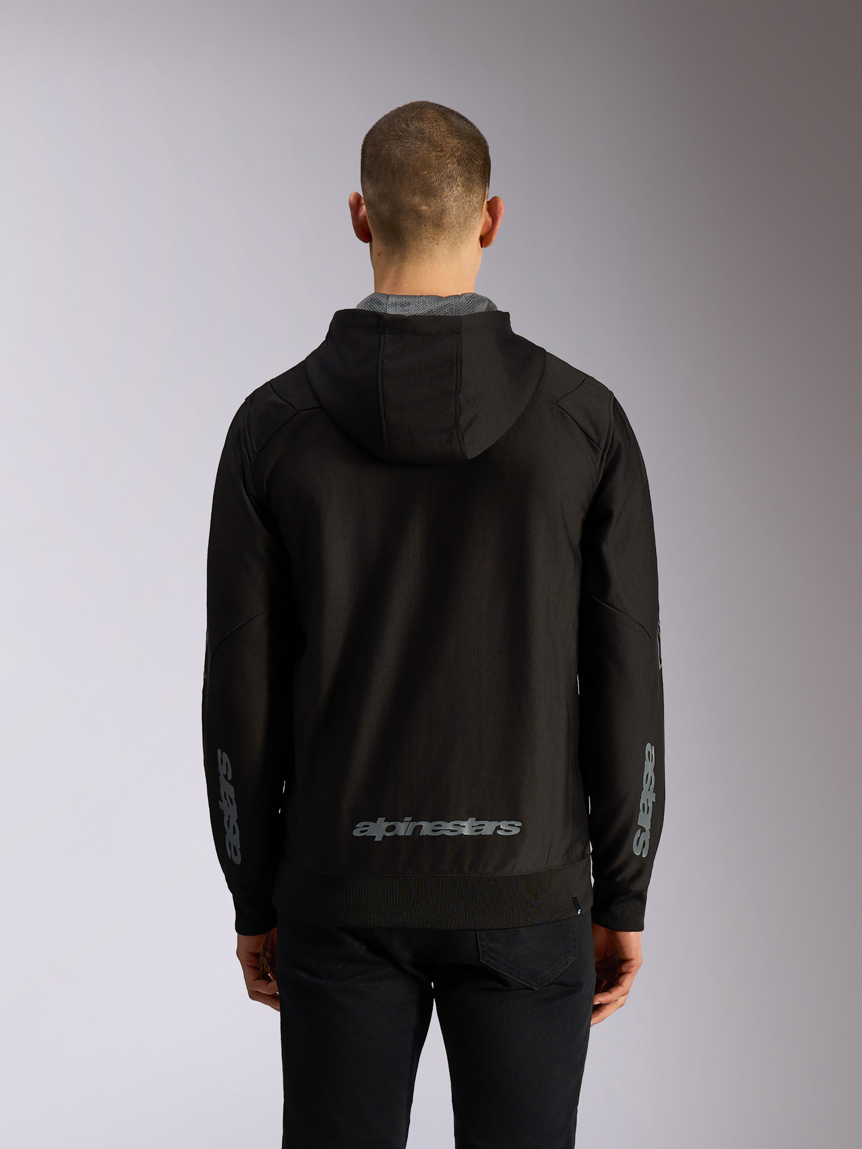 Alpinestars Sessions V3 Hoodie, Rückansicht, schwarze Kapuzenjacke mit Reißverschluss, grauer Alpinestars-Schriftzug am unteren Rücken, Astars-Branding auf den Ärmeln, Rippbündchen an Saum und Ärmeln, lässige Motorsport-Streetwear