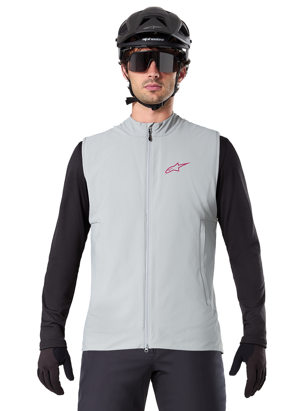 Alpinestars A-Dura Thermoweste, Rad-Gilet, Titangrau, getragen mit schwarzem Langarm-Trikot und schwarzem Fahrradhelm, rotes Alpinestars-Sternlogo auf der Brust, leicht und isoliert fürs Mountainbiken.