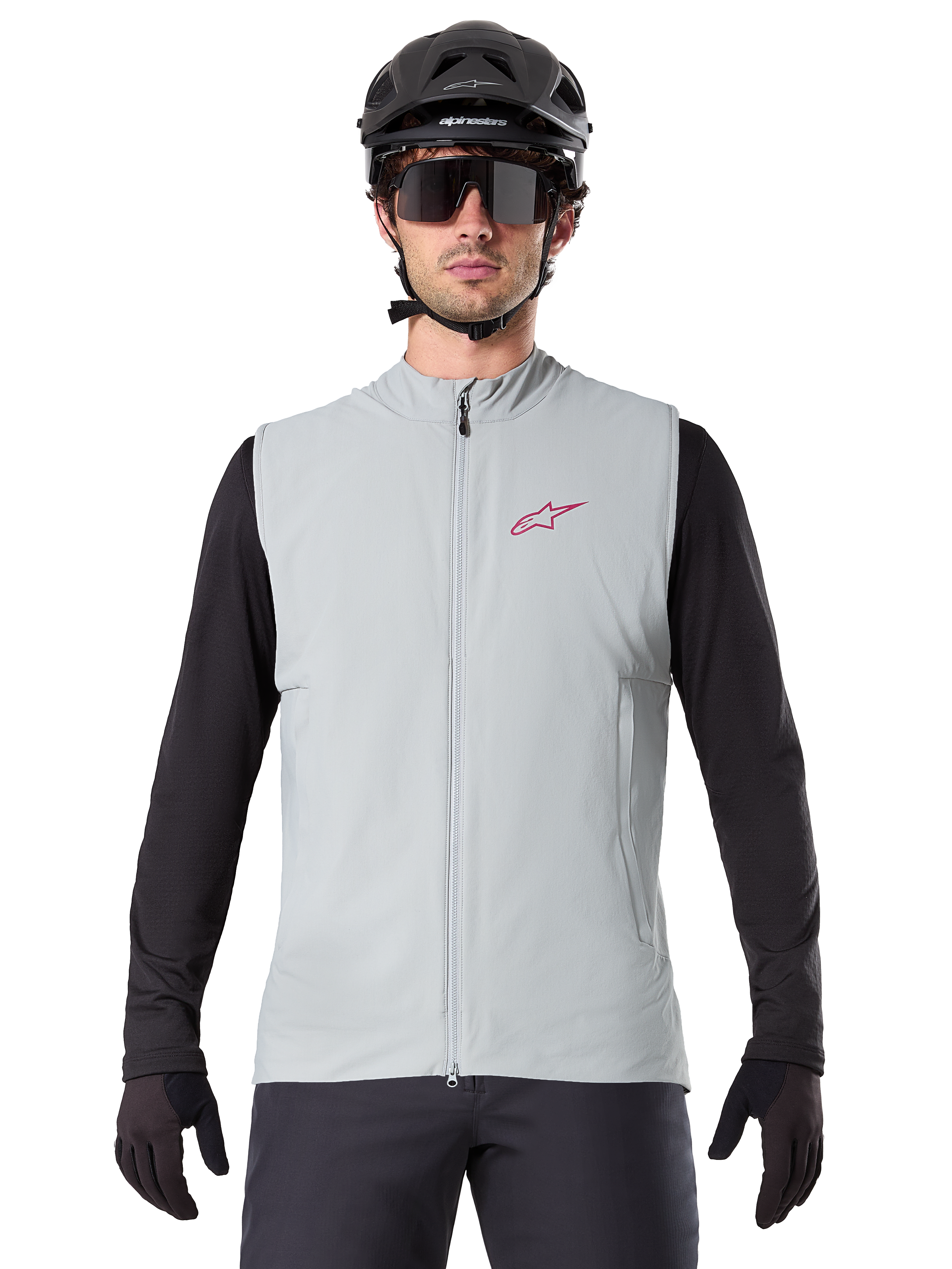 Alpinestars A-Dura Thermoweste, Rad-Gilet, Titangrau, getragen mit schwarzem Langarm-Trikot und schwarzem Fahrradhelm, rotes Alpinestars-Sternlogo auf der Brust, leicht und isoliert fürs Mountainbiken.